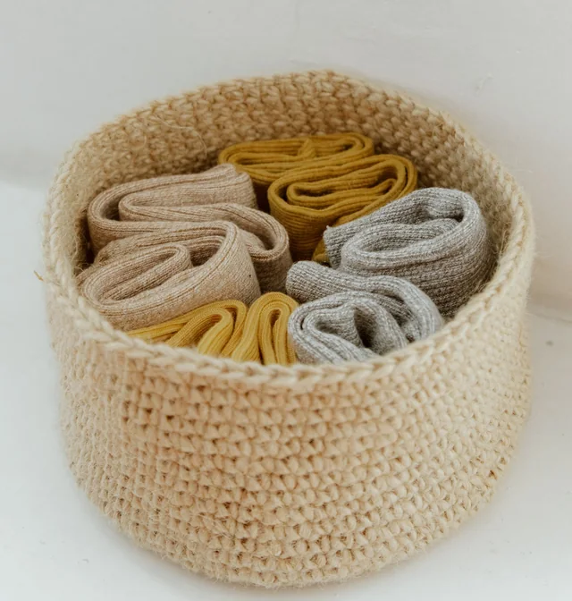 Rolled everyday socks in a knitted basket